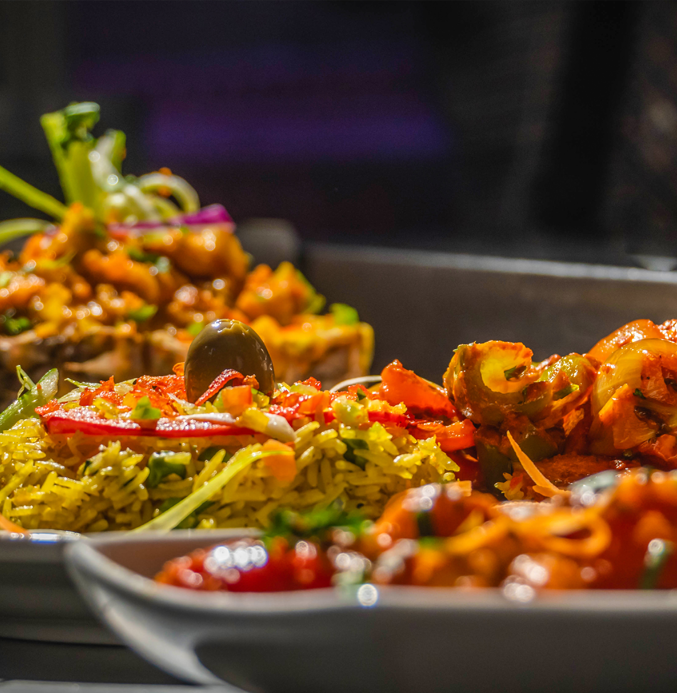 Close-up of a vibrant buffet with yellow rice and colorful vegetables in the foreground.