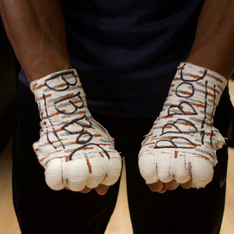 Close-up of a person wearing white boxing wraps over both fists, ready for training or sparring.